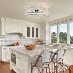 a kitchen with white cabinets and an island in front of two windows that overlook the water