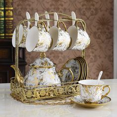 there is a tea set with cups and saucers on the stand, next to a cup holder