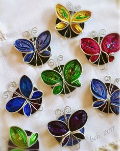 six colorful butterfly brooches sitting on top of a white cloth