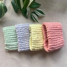 four crocheted headbands sitting on top of a table next to a potted plant