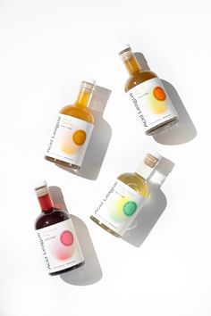 three bottles of different colored liquids on a white surface