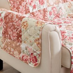 a white couch with a floral quilt on it