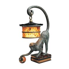 a lamp that has a cat on top of it with a ball in front of it