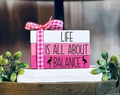 a pink and white sign that says life is all about balance on top of a wooden box