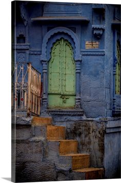 an old blue building with steps leading up to the door and stairs in front of it