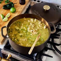 a pot filled with soup sitting on top of a stove next to a cutting board