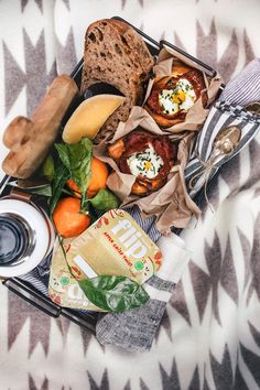 a basket filled with different types of food on top of a bed next to a cup of coffee