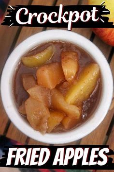 a white bowl filled with fried apples on top of a wooden table next to an apple