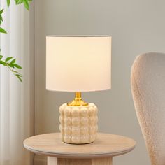 a white table lamp sitting on top of a wooden table