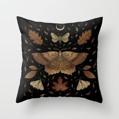 a black pillow with an image of a moth on it's back and leaves around it