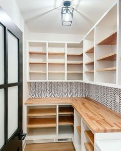 an empty walk in closet with wooden shelves