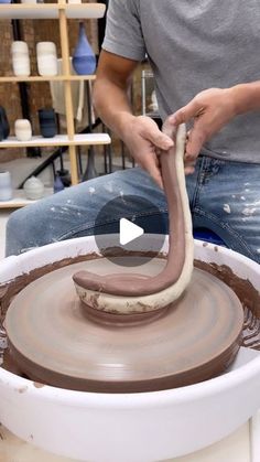 a man working on a pottery wheel with a snake coming out of the top one