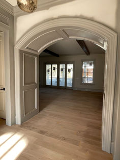 an empty living room with wood floors and white trim on the doors, windows, and doorways