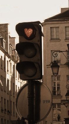 a traffic light with a heart on it in the middle of an urban area,