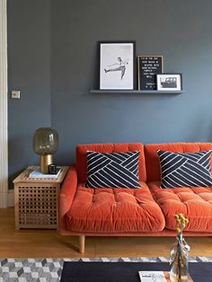 a living room with blue walls and orange couches on the floor, in front of an open door