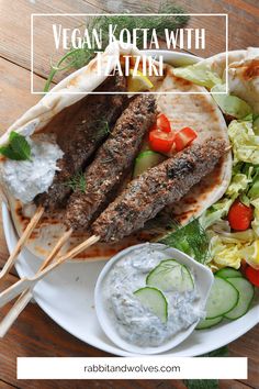 a white plate topped with meat and veggies next to a bowl of ranch dressing