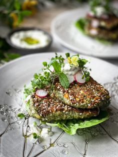 two white plates topped with food and veggies