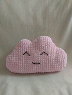 a pink cloud pillow with eyes drawn on it