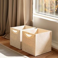 two brown boxes sitting on top of a wooden floor next to a window sill