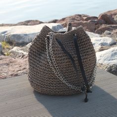 a crocheted purse sitting on top of a wooden table next to the ocean