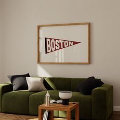 a living room with a green couch and wooden coffee table in front of a framed boston sign