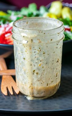 a glass jar filled with food sitting on top of a table next to a fork