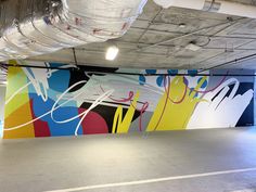 an empty parking garage with graffiti painted on the wall and ceiling, along with no people