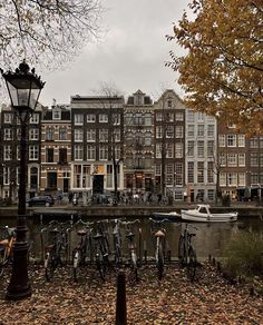 many bicycles are parked next to the water in front of some buildings with boats on it