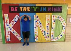 a young boy standing in front of a colorful wall with the words be the i'm in kind written on it