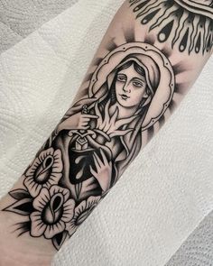 a black and white tattoo with an image of the virgin mary on it's arm