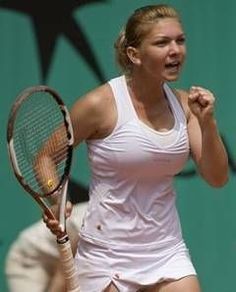 a woman holding a tennis racquet on top of a tennis court with other people in the background