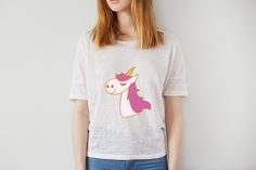 a woman wearing a white t - shirt with a pink unicorn on it