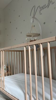 a baby crib with white sheets and polka dots on the wall behind it,