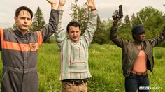 three men standing in a field holding up their hands with one man raising his arms