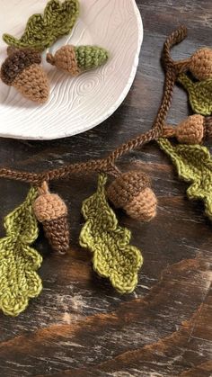 crocheted acorns and leaves are hanging from a string on a wooden table