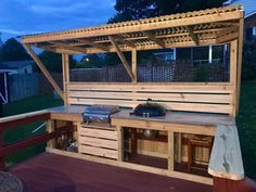 an outdoor kitchen made out of pallet wood with grill and sink on the side