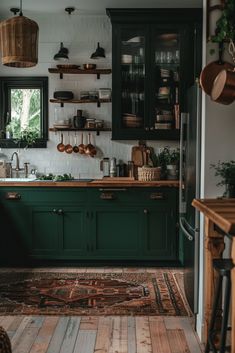 a kitchen with dark green cabinets and wooden floors is pictured in this image, there are potted plants on the counter