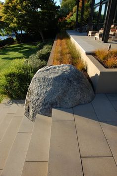 a rock sitting on top of a sidewalk next to grass