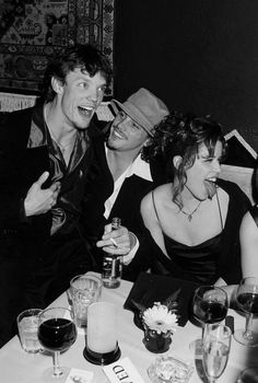 black and white photograph of three people sitting at a table with wine glasses in front of them