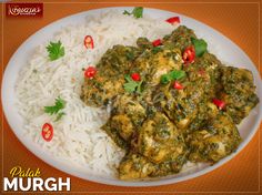 a white plate topped with rice and meat covered in green sauce next to red peppers