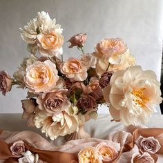 a vase filled with lots of pink flowers on top of a white table cloth covered table