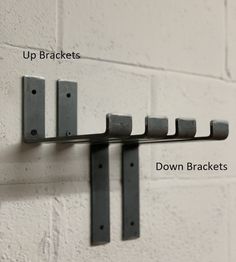 a metal rack with five brackets attached to the side of a white brick wall, labeled up brackets and down brackets