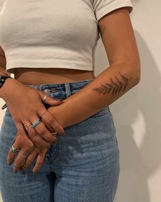 a woman with tattoos on her arm holding onto her jeans and showing off her tattoo