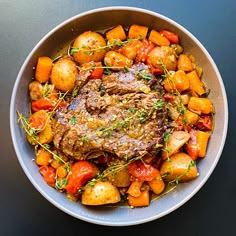 a bowl filled with meat, potatoes and carrots