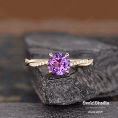 an amethorate ring with diamond accents on top of a black stone slab