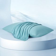 a white round bed with blue sheets and pillows