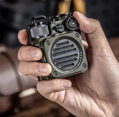 a person holding an old fashioned radio in their hand and looking into the camera lens