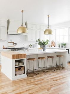 a kitchen island with stools in front of it and three hanging lights above it