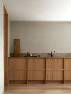 an empty kitchen with wooden cabinets and counter tops in the center, along with white walls