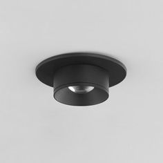 a black circular light fixture on a white wall